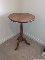 Full view of one pedestal side table showing round top and tripod legs