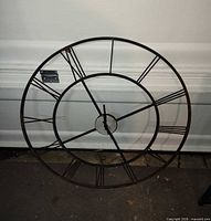 Front view of round metal clock frame with Roman numerals