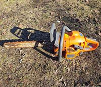 Left side view of entire chainsaw showing bar, chain, housing