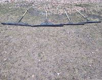 Row of five long handled squeegees laid out on ground