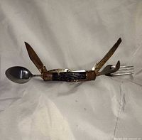 Multi-tool open showing knife, spoon, fork, saw, opener