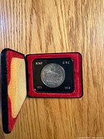 Open case showing 1973 RCMP commemorative dollar coin and date panel