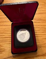 Coin in open presentation case showing reverse design and inscriptions