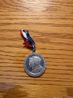 Obverse of aluminum medal showing King George VI profile and surrounding legend, ribbon attached