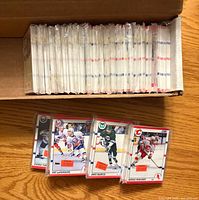Cardboard box with multiple stacks of sleeved 1990-91 Score hockey cards; four individual sleeved cards displayed in front