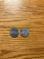 Fronts of two 1969 Canada $1 Voyageur coins on wood background