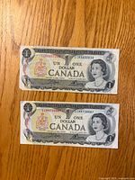 Front side of both 1973 $1 bills showing serials and Queen Elizabeth II portrait