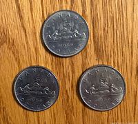 Obverse sides of three 1969 Canadian dollars showing Voyageur canoe design