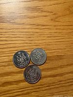 Three Canadian 50-cent coins reverse side showing Coat of Arms