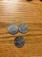 Three Canadian 50-cent coins showing reverse Coat of Arms