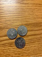 Reverse side of three 1984 Canadian 50-cent coins displaying Canadian coat of arms