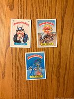 Fronts of the three Garbage Pail Kids cards