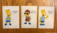 Front view of three Bart Simpson postcards showing different slogans