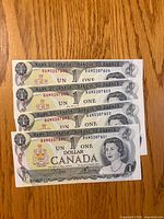 Fronts of four consecutive 1973 Canada $1 banknotes showing serial numbers and Queen Elizabeth II portrait