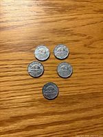 Five beaver-reverse 1953 Canadian 5-cent coins laid out on wood surface