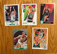 Fronts of five Larry Bird basketball cards on wood surface