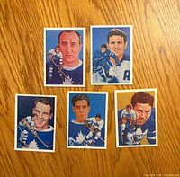 Fronts of all five illustrated Maple Leafs Hall of Fame cards laid out on wood surface