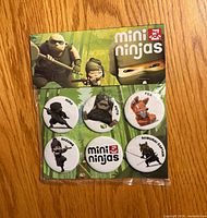 Front view of sealed pack showing six Mini Ninjas buttons on card