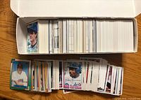 Open card storage box filled with sorted baseball cards; additional loose stack showing card fronts