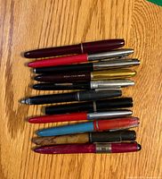 Stacked front view of 10 closed fountain pens on wood surface