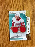 Front of Upper Deck Artifacts Rookie Taro Hirose card showing player image, two red jersey swatch windows, serial number 331/499