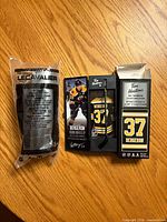 Both packaged mini hockey sticks on wood surface; Bergeron boxed stick displayed front and back, Lecavalier stick in plastic bag