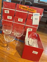 Stack of ten sealed red Baccarat boxes with three unboxed goblets in front