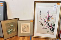 All three framed embroidery artworks standing against wall