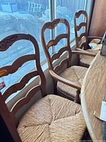 Three matching wood ladder-back chairs with rush seats by window
