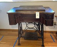 Front view of closed wooden cabinet on cast-iron treadle base