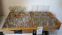 Two boxes containing mixed goblets, mugs, tumblers