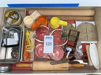 Drawer view of entire assortment: rolling pins, measuring cups, utensils, tins
