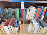 Overall view of two shelves showing quantity and variety of books, clear bins in front