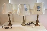 Three brass table lamps with shades on table