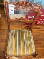 Front view of carved wooden dining chair with striped seat