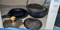Overall lot: pot with lid, skillet, trivet, bacon press visible