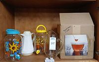 Full lot in cabinet: two printed dispensers, white pitcher, clear pitcher, boxed punch bowl set