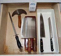 Drawer view showing rocker knife, honing steel, two cleavers, chef’s knife and bread knife