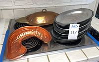 Entire lot showing copper platter, fish mold, stack of cast iron sizzling plates and wooden underliners