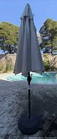 Full view of closed umbrella on stand next to pool