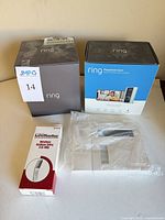 Four security items: Ring Peephole Cam box, Ring Spotlight Cam box, LiftMaster keypad package, Honeywell keypad (wrapped) grouped
