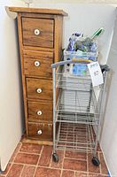 Front view of wooden cupboard, wire cart, cleaning supplies in caddy