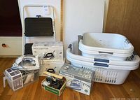 Group view of boxed Rowenta irons, GE travel iron box, soleplate kit, plastic baskets, step stool, washcloth bin