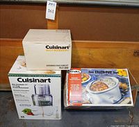 Three boxed items: Cuisinart feed tube kit, Cuisinart Pro Custom 11 food processor, Rival oval Crock-Pot slow cooker