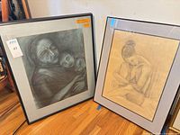 Front view of both framed drawings leaning against wall