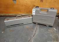 Both closed carry cases: silver metal Tiger Cub box and grey Porter-Cable molded case