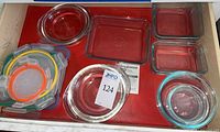 Drawer view with assorted round bowls, square dishes and stack of multicolour lids