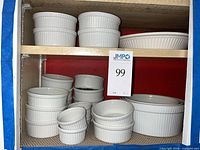 Shelf with multiple white ribbed ramekins and casserole dishes