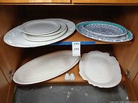Cabinet shelf with all eight platters and plates visible for overall view and count verification