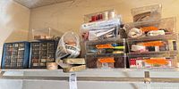 Shelf with blue drawer organizer, clear drawer units, boxes of thread, rolls of tape